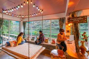 a group of people sitting in a room with a swing at Zostel Plus Mussoorie- Kempty in Mussoorie