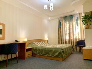 a bedroom with a bed and a desk and a window at Business Hotel Kostroma in Kostroma