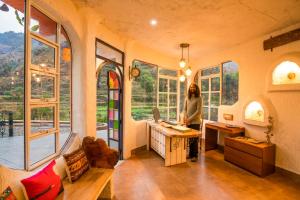 a woman standing at a desk in a room with windows at Zostel Plus Mussoorie- Kempty in Mussoorie