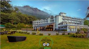 a large hotel with a mountain in the background at Sterling Munnar in Munnar