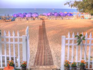 une clôture blanche sur une plage avec des parasols dans l'établissement Estrela Do Mar Beach Resort - A Beach Property, à Calangute