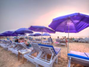 a group of blue umbrellas and chairs on a beach at Estrela Do Mar Beach Resort - A Beach Property in Calangute