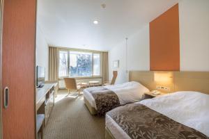 a hotel room with two beds and a desk at Kyukamura Nikko-Yumoto in Nikko