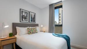 a bedroom with a white bed and a window at Oaks Melbourne Southbank Suites in Melbourne