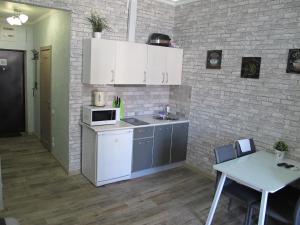 アドレルにあるApartment on Bulvar Nadezhd 6/2のキッチン(白いキャビネット、テーブル、テーブル、電子レンジ付)