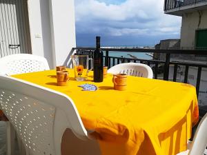 a yellow table with a bottle of wine and glasses on a balcony at Casa vacanze afrodite centro storico Otranto, Salento 6 posti in Otranto