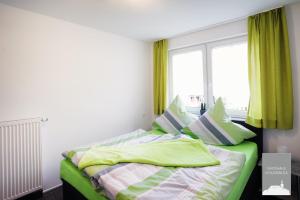 Schlafzimmer mit einem Bett mit grüner Bettwäsche und einem Fenster in der Unterkunft Gästehaus Schlossblick Greiz in Greiz