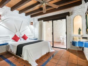 a bedroom with a large white bed with red pillows at Capital O Mimi Del Mar, Playa del Carmen in Playa del Carmen