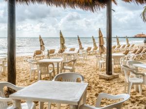 un grupo de mesas y sillas en la playa en Capital O Mimi Del Mar, Playa del Carmen en Playa del Carmen