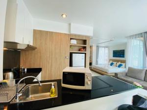 a kitchen with a microwave and a living room at Buasri By Ohm in Patong Beach