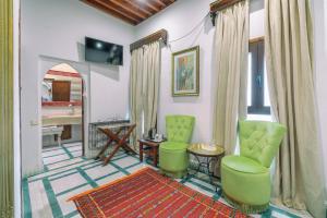 a living room with green chairs and a table at Dar Baibou in Chefchaouen