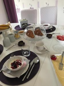 una mesa con platos y tazones de comida. en PIVOINE Chambre d hotes, en Fralignes