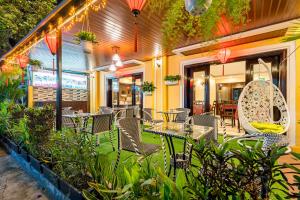 a restaurant with tables and chairs and plants and lights at Golden River Hotel in Hoi An