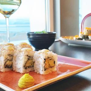 a plate of sushi on a table with a glass of wine at Hotel Höfn in Höfn