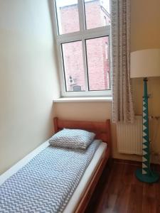 a small bed in a room with a window at Hostel Orange Plus in Toruń