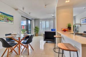 uma cozinha e sala de estar com mesa e cadeiras em Darwin Waterfront Luxury Apartment em Darwin