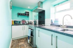 a kitchen with blue walls and a sink and a stove at Host & Stay - Daisy Cottage in Bamburgh +12 photos