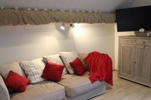 een woonkamer met een bank met rode kussens bij La petite maison dans la cour in Stave
