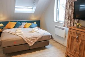 een slaapkamer met een bed met blauwe en gele kussens bij La petite maison dans la cour in Stave