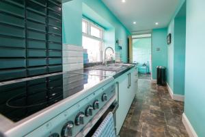 a large kitchen with blue walls and a sink at Host & Stay - Daisy Cottage in Bamburgh