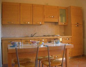 una cucina con tavolo, sedie e armadi in legno di Terrazze sul Mare alla Ciaccia - Apartment 4 a Codaruina