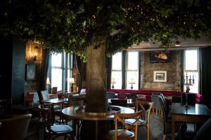 een boom in het midden van een restaurant met tafels en stoelen bij The Portland in Ashington