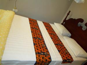 a bed with a blanket on top of it at KERESI BLOCK At PENIEL BEACH HOTEL in Entebbe