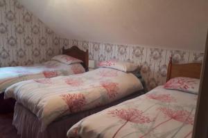 2 camas en una habitación con papel pintado en Bessies Cottage, en Ahoghill