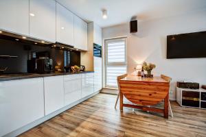 een keuken met witte kasten en een houten tafel bij Helen Apartament Staromiejski in Toruń