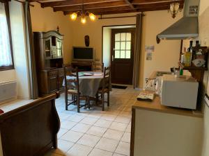 Aucairn في Château-Verdun: مطبخ وغرفة طعام مع طاولة وتلفزيون