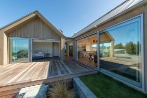 a house with a large deck with glass doors at Villa Kaki in Lake Tekapo