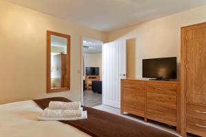 1 dormitorio con 1 cama, TV y espejo en Swan Place Apartments By Viridian Apartments, en Swindon