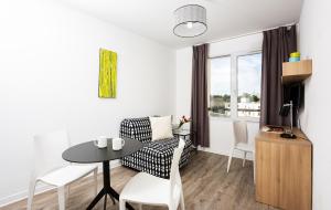 a living room with a table and a chair at Ténéo Apparthotel Talence in Talence