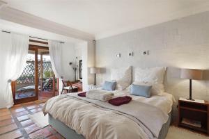 1 dormitorio con 1 cama grande con sábanas blancas y almohadas azules en Bayview Mountain Seafacing Cottages en Hout Bay