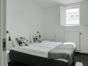 Bett in einem weißen Zimmer mit Fenster in der Unterkunft Gamla Televerket B&B in Borgholm