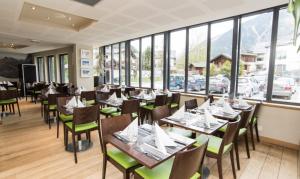 een restaurant met houten tafels, stoelen en ramen bij Hotel Les Lanchers in Chamonix-Mont-Blanc