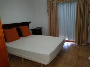 a bedroom with a large white bed with orange pillows at Villa Papagayo in Playa Blanca
