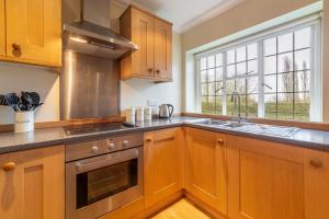 a kitchen with wooden cabinets and a stove top oven at Higham Place Lodge in Higham
