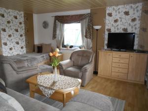 a living room with a couch and chairs and a tv at Müller's Ferienwohnungen in Rödental