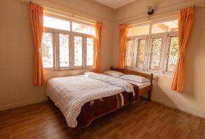 a bedroom with a bed and two windows at New Tourist Guest House in Pokhara