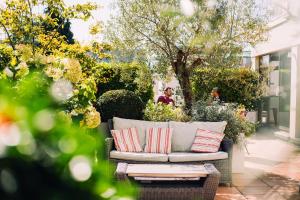 a wicker couch with pillows sitting on a patio at The Club Hotel & Spa Jersey in Saint Helier Jersey