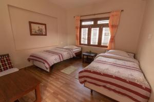 2 letti in una camera con finestra di New Tourist Guest House a Pokhara Altre 4 foto