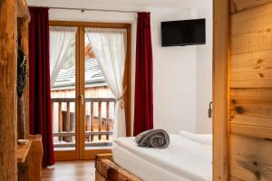 a bedroom with a bed and a window with red curtains at B&B Sot l'Agner - Ospitalità Diffusa Conca Agordina in Taibon