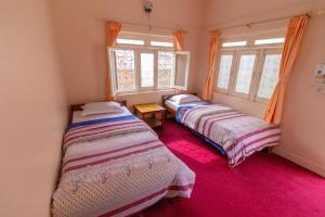 two beds in a room with two windows at New Tourist Guest House in Pokhara