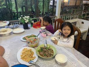 zwei Kinder sitzen an einem Tisch mit Tellern voller Essen in der Unterkunft Cast Away in Nonthaburi