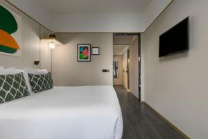 a bedroom with a large white bed and a flat screen tv at Be Mate Paseo de Gracia in Barcelona