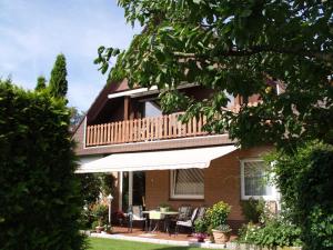 a house with a balcony and a table and chairs at Ferienwohnung Mona, 65314 in Moormerland