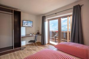 een slaapkamer met een bed en een bureau met een raam bij Apartments Zauberberg in Hainzenberg