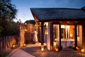 una mujer parada fuera de un baño con bañera en Kwandwe Great Fish River Lodge, en Grahamstown