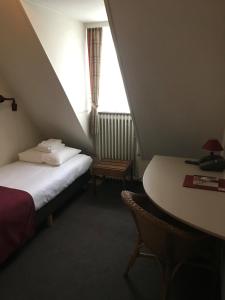 a room with a bed and a table and a window at Abdij Hotel Rolduc in Kerkrade